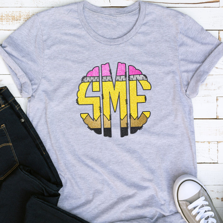 Heather gray monogram school pencil shirt with round 3 letter monogram in the middle.  Each letter of the monogrammed shirt looks like a colorful school pencil.
