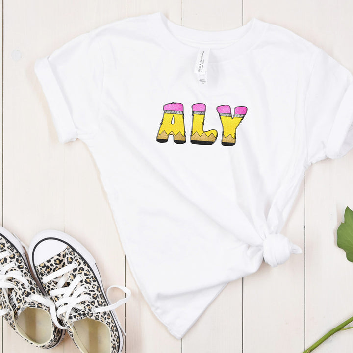 Youth white personalized name shirt for back to school with doodle letters that resemble school pencils to spell out your childs name.
