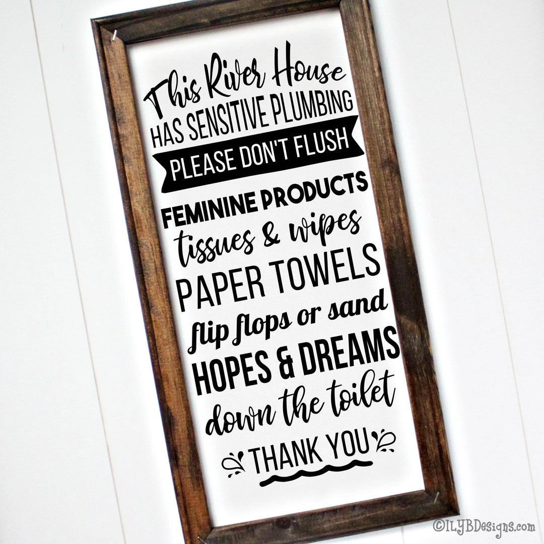 Wooden-framed canvas sign with humorous bathroom rules text for a river house with sensitive plumbing on a white background