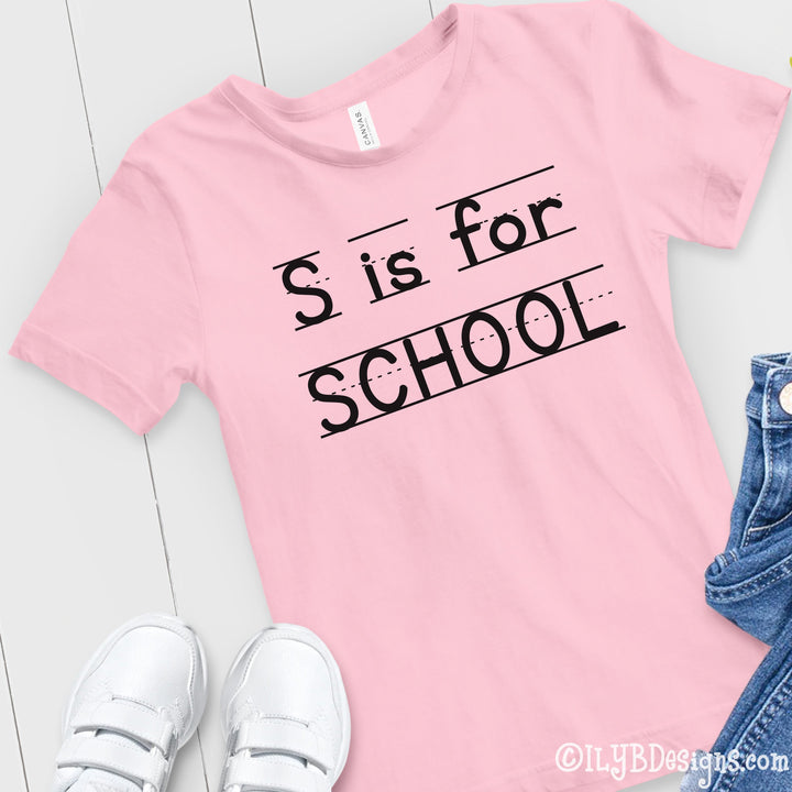 Light pink S is for School back to school shirt with a playful print font, complete with elementary lined writing lines. Design is in black.