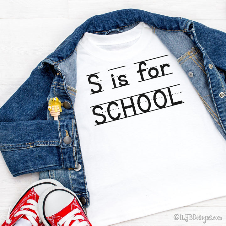 White S is for School back to school shirt with a playful print font, complete with elementary lined writing lines. Design is in black.