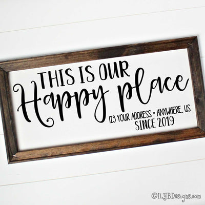Dark walnut stained 20"x10" frame on a white canvas with black words in a mix of script and print fonts. It reads, "This Is Our Happy place, with an address line, since 2019." The design is placed horizontally on the sign.