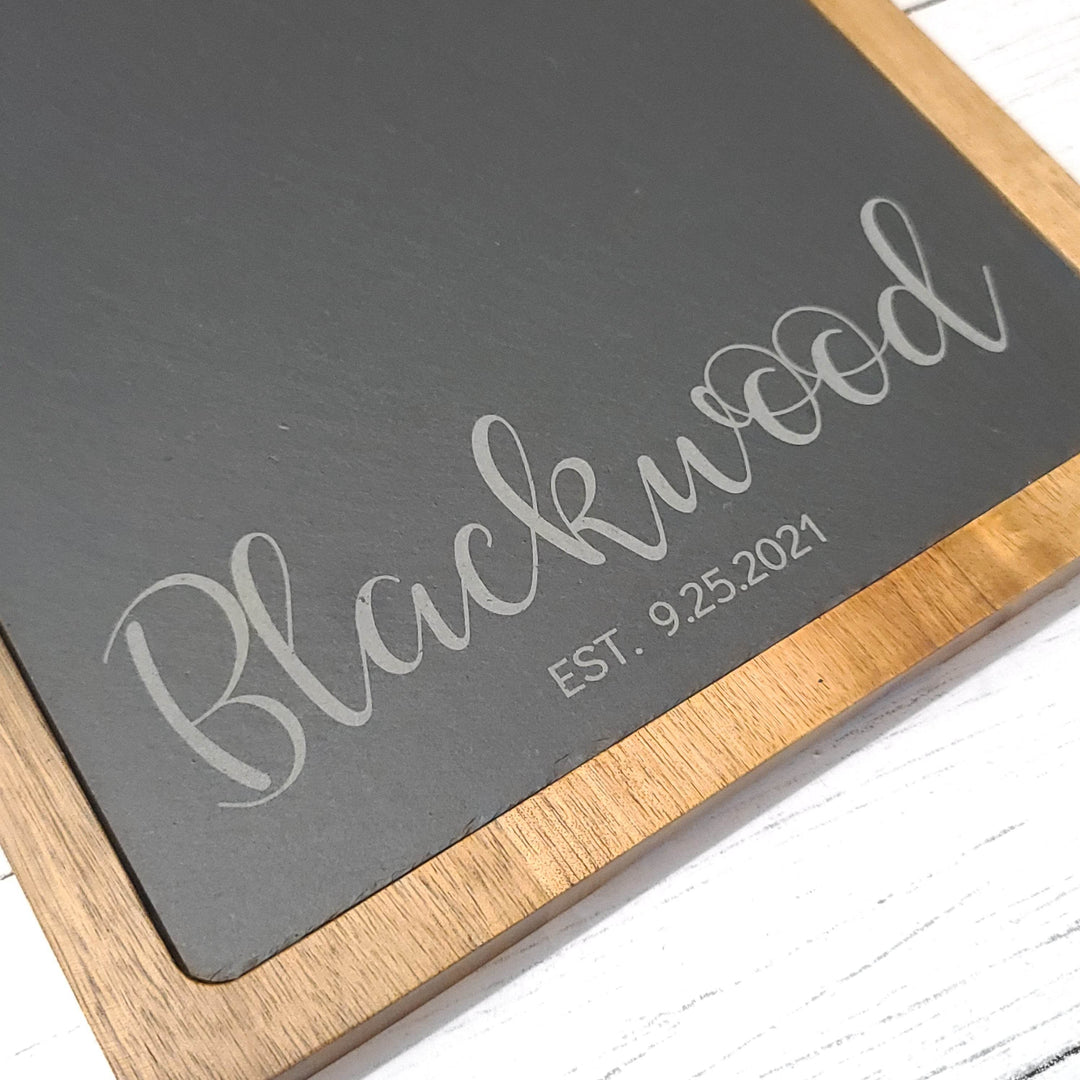 closeup of wood and slate charcuterie board with couples name and established date engraved in slate
