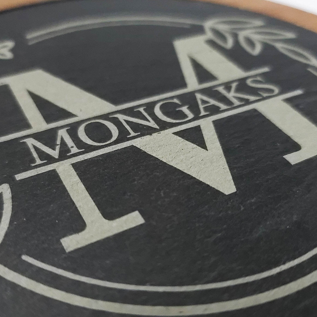 Close-up of a slate cheese board with engraved floral monogram initial and last name